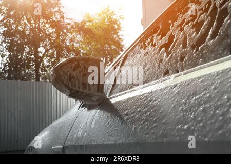 Auto mit Reinigungsschaum in der Außenwaschanlage, Nahaufnahme Stockfoto