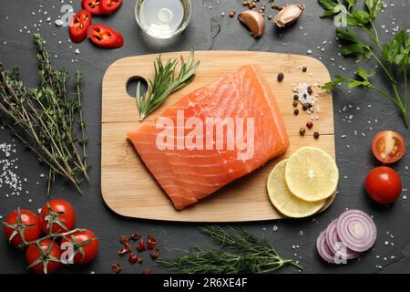 Frischer roher Lachs und Zutaten für Marinade auf schwarzem Tisch, flach liegend Stockfoto