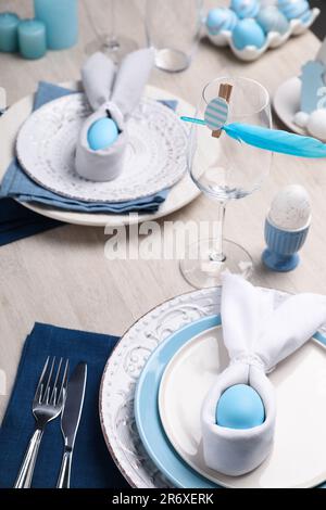 Festlicher Tisch mit Hasenohren aus hellblauen Eiern und Servietten. Osterfeier Stockfoto