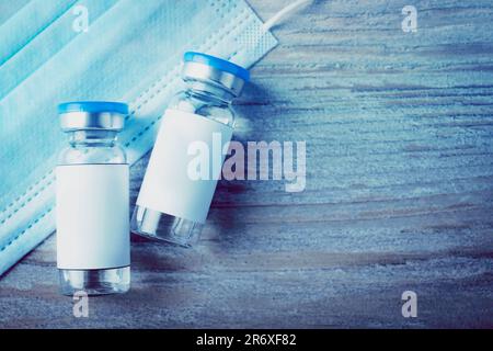 Medikation in Glasfläschchen und Maske auf Holztisch, Draufsicht und Platz für Text. Farbton Stockfoto