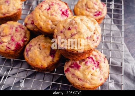 Frisch gebackene Himbeermuffins, die sich auf einem Kühlregal stapeln: Frühstücks- oder Dessert-Muffins, die mit Früchten aus der Vogelperspektive zubereitet werden Stockfoto