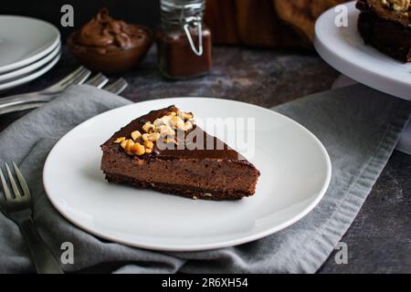 Dunkle Schokolade und Haselnuss-Mousse-Kuchen auf einem weißen Teller mit einer Gabel Stockfoto