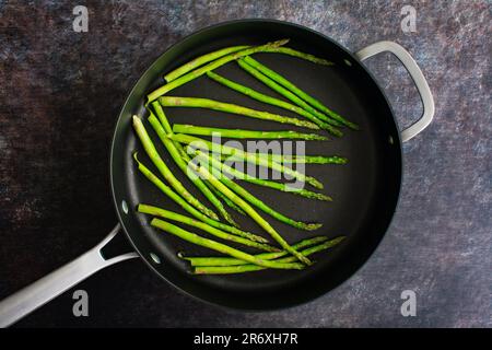 Frischer Spargel in einer großen Sautenpfanne mit Antihaftbeschichtung kochen: Dünne Spargelspieße in einer großen Pfanne braten Stockfoto