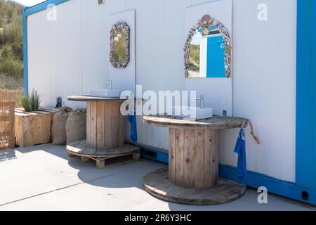 Entlang eines Containers gibt es zwei Waschbecken auf einer Holzrolle am Strand im Freien Stockfoto