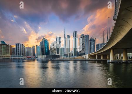 Die Skyline von Dubai. Abendstimmung in der arabischen Stadt. Sonnenuntergang mit Wolkenkratzern in den Emiraten mit Blick auf Burj Khalifa. Verglaste Fassade von Wolkenkratzern. Brücke Stockfoto