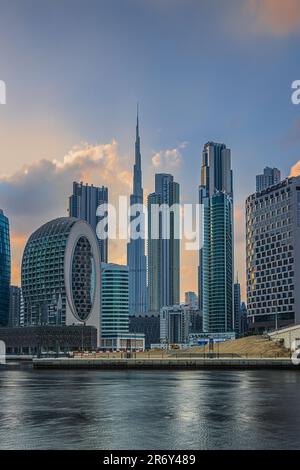 Blick auf die Wolkenkratzer mit Burj Khalifa von Dubai. Die arabische Skyline am Abend. Abendstimmung mit bewölktem Himmel bei Sonnenuntergang. Hafen und Kanal Stockfoto