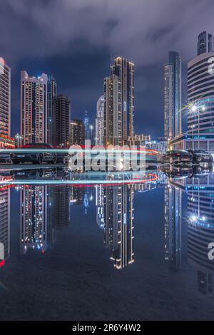Bürogebäude im Zentrum von Dubai bei Nacht. Beleuchtete Wolkenkratzer in den Vereinigten Arabischen Emiraten zur Blue Hour. Reflexionen des Lichts Stockfoto