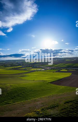 Endlose grüne Felder von oben mit atemberaubendem Himmel und untergehender Sonne Stockfoto