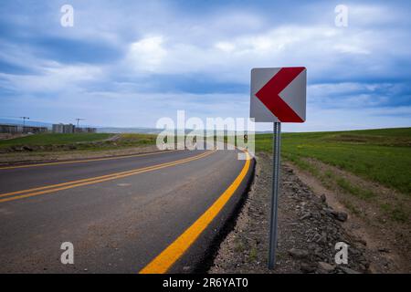 Neu gepflasterte, hochwertige kurvenreiche Straße mit gelben Linien und Abbiegehindern Stockfoto