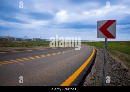 Neu gepflasterte, hochwertige kurvenreiche Straße mit gelben Linien und Abbiegehindern Stockfoto