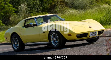 Stony Stratford, Großbritannien - Juni 4. 2023: 1974 gelbe GENERAL MOTORS CHEVROLET CORVETTE STINGRAY Klassiker, die auf einer englischen Landstraße fahren. Stockfoto