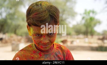 Farbenfrohes, lustiges Gesicht eines indischen Kindes beim holi Festival. Holi feiert indischen kleinen Jungen, der Holi spielt und Gesichtsausdruck zeigt. Stockfoto