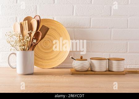 Keramikbecher mit Bambusdeckel und Zuckerdose, Becher mit Holzlöffeln auf Holzablagefläche im Inneren einer modernen, umweltfreundlichen Küche Stockfoto