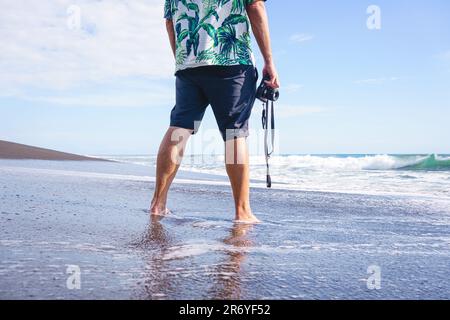 Zugeschnittenes Foto mit Kopierraum eines unbekannten Mannes mit einer Kamera zum Meer Stockfoto