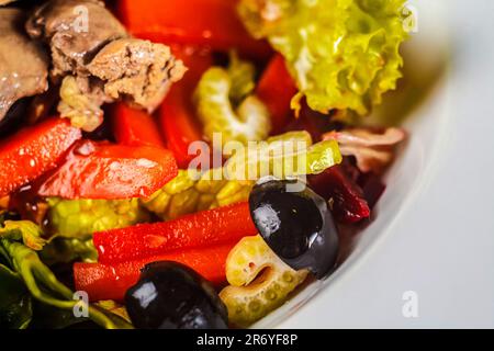 Ein farbenfroher, frisch zubereiteter Salat gefüllt mit Oliven, roten Paprika und anderem Gemüse für eine köstliche und nahrhafte Mahlzeit, die gesundes Essen fördert Stockfoto