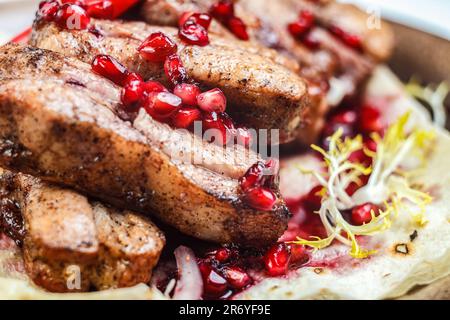 Ein köstliches geröstetes Schweinefleisch mit Granatäpfeln, Preiselbeeren und anderen Früchten für ein gesundes Frühstück. Stockfoto