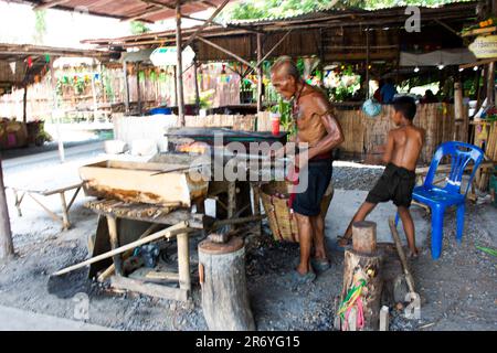 Thailändische alte Schmied- oder Metallschmied, die in der lokalen Schmiede-Werkstatt des Dorfes Bang Rachan antike Waffen aus Eisen und Stahl herstellen Stockfoto