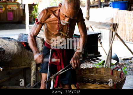 Thailändische alte Schmied- oder Metallschmied, die in der lokalen Schmiede-Werkstatt des Dorfes Bang Rachan antike Waffen aus Eisen und Stahl herstellen Stockfoto