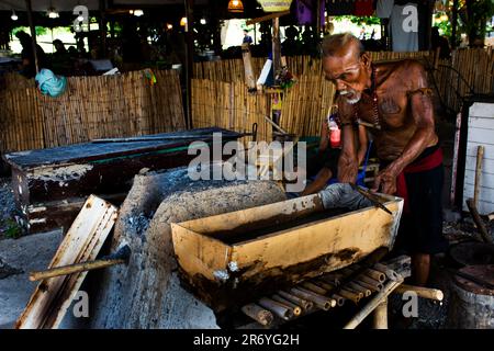 Thailändische alte Schmied- oder Metallschmied, die in der lokalen Schmiede-Werkstatt des Dorfes Bang Rachan antike Waffen aus Eisen und Stahl herstellen Stockfoto