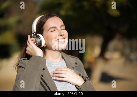 Glückliche Frau, die mit dem Kopfhörer läuft und Musik hört Stockfoto