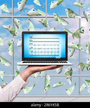 Handgehaltener Laptop mit Anwendungsformel und fallenden Euro-Scheinen Stockfoto