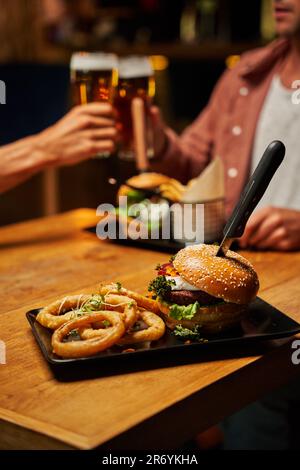 Nahaufnahme eines jungen weißen Paares in legerer Kleidung mit Fast Food und Bier im Restaurant Stockfoto