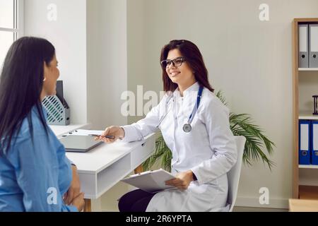 Brillenärztin lächelt und erklärt Ergebnisse der positiven Behandlungsdynamik nach der Untersuchung. Stockfoto