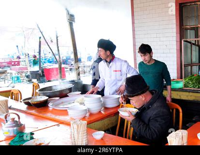 Ein kleines Straßenrestaurant, das Lagman-Nudeln und Reis mit Teigtaschen auf einem wöchentlichen Viehmarkt in den Außenbezirken von Kashgar, Xinjiang, China, serviert. Stockfoto