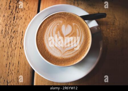 Eine Nahaufnahme von Latte-Kaffee auf dem Holztisch mit einem unscharfen Hintergrund Stockfoto
