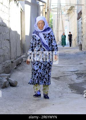 Eine usbekische Frau, die in der Altstadt von Bukhara, Usbekistan, spaziert. Stockfoto