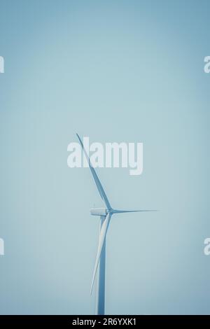 Eine große weiße Windturbine steht vor einem strahlend blauen Himmel Stockfoto