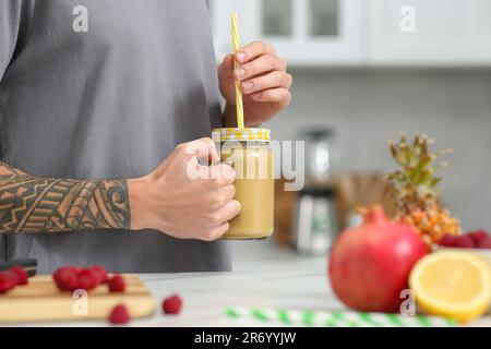 Mann mit leckerem Smoothie in der Küche, Nahaufnahme. Platz für Text Stockfoto