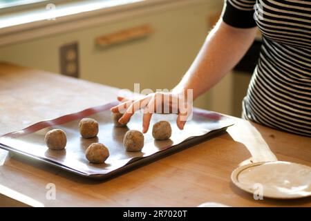 Eine Frau legt eine frische Kugel weihnachtskeksteig auf ein Keksblatt in ihrer Küche in Seattle, Washington. Stockfoto