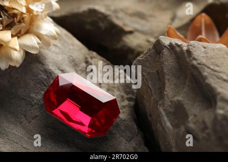 Wunderschöner roter Edelstein für Schmuck auf Steinoberfläche, Nahaufnahme. Platz für Text Stockfoto