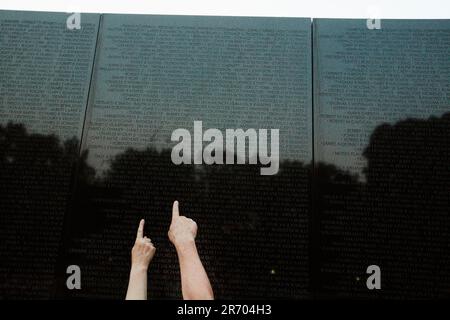 Die Leute berühren und zeigen auf Namen an der Vietnam Veterans Memorial Wall in Washington, DC. Stockfoto