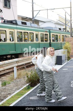 Junge japanische Frauen tanzen auf den Gleisen der Enoshima Electric Railway in der Nähe von Kamakura, Japan. Stockfoto