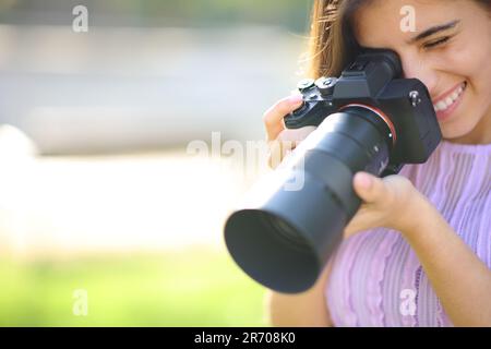 Glücklicher Fotograf, der ein Foto in einem Park mit Kopie macht Stockfoto