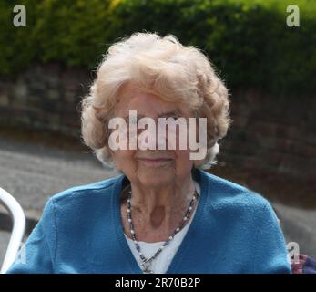 Porträt einer hundertjährigen Frau, die auf der King Charles III Coronation Street Party Surrey England lächelt Stockfoto