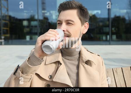 Ein hübscher Mann, der draußen aus der Blechdose trinkt Stockfoto