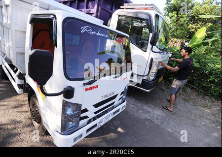 10. Juni 2023, Kulonprogo, Yogyakarta, Indonesien: Ein Mini-Lkw fährt am 12. Juni 2023 vor einem echten Lkw im Dorf eines Einwohners in Kulonprogo, Yogyakarta. Der Lkw verwendet einen modifizierten Motorradmotor. Der Spielzeugwagen ist so konstruiert, dass er im Allgemeinen einem Lkw ähnelt, hat jedoch wesentlich kleinere Abmessungen mit Vorwärts-, Rückwärts- und Hubfunktionen hinter dem Bett. Ein junger Mann namens Imam, Eigentümer von Rimbono Garage, sagte, dass der Zweck der Herstellung des Mini-Lkws anfangs nur darin bestand, Fananfragen in sozialen Medien zu erfüllen. Denn vor der Herstellung von Spielzeugautos war die Karosserie des Lkws rein handgefertigt Stockfoto