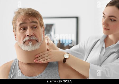 Orthopädin, der das Halsband am Hals des Patienten in der Klinik anlegt Stockfoto