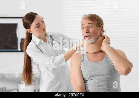 Orthopädin, der das Halsband am Hals des Patienten in der Klinik anlegt Stockfoto