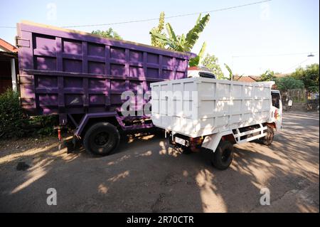 10. Juni 2023, Kulonprogo, Yogyakarta, Indonesien: Ein Mini-Lkw fährt am 12. Juni 2023 vor einem echten Lkw im Dorf eines Einwohners in Kulonprogo, Yogyakarta. Der Lkw verwendet einen modifizierten Motorradmotor. Der Spielzeugwagen ist so konstruiert, dass er im Allgemeinen einem Lkw ähnelt, hat jedoch wesentlich kleinere Abmessungen mit Vorwärts-, Rückwärts- und Hubfunktionen hinter dem Bett. Ein junger Mann namens Imam, Eigentümer von Rimbono Garage, sagte, dass der Zweck der Herstellung des Mini-Lkws anfangs nur darin bestand, Fananfragen in sozialen Medien zu erfüllen. Denn vor der Herstellung von Spielzeugautos war die Karosserie des Lkws rein handgefertigt Stockfoto