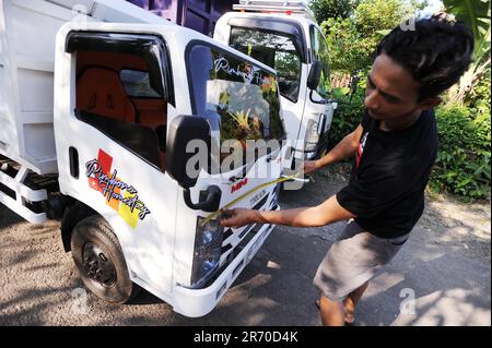 10. Juni 2023, Kulonprogo, Yogyakarta, Indonesien: Ein Mini-Lkw fährt am 12. Juni 2023 vor einem echten Lkw im Dorf eines Einwohners in Kulonprogo, Yogyakarta. Der Lkw verwendet einen modifizierten Motorradmotor. Der Spielzeugwagen ist so konstruiert, dass er im Allgemeinen einem Lkw ähnelt, hat jedoch wesentlich kleinere Abmessungen mit Vorwärts-, Rückwärts- und Hubfunktionen hinter dem Bett. Ein junger Mann namens Imam, Eigentümer von Rimbono Garage, sagte, dass der Zweck der Herstellung des Mini-Lkws anfangs nur darin bestand, Fananfragen in sozialen Medien zu erfüllen. Denn vor der Herstellung von Spielzeugautos war die Karosserie des Lkws rein handgefertigt Stockfoto