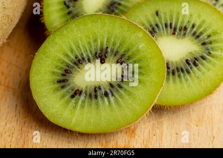 Eine Gruppe geschnittener grüner Kiwifrüchte mit schwarzen Samen, Details von in Stücke geschnittenem grünem Kiwipulp Stockfoto