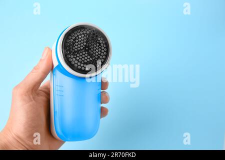 Frau mit modernem Textilrasierer auf hellblauem Hintergrund, Nahaufnahme. Platz für Text Stockfoto