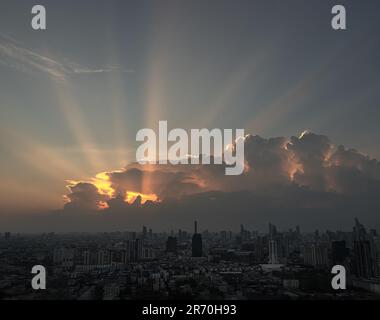 Göttliches Leuchten durch die Wolken der warmen Sonne am Morgen oder Abend über der großen Metropolitan City mit Wolkenkratzern im Hintergrund. Die atemberaubende Schönheit von Stockfoto