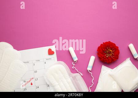 Menstruationskalender mit Baumwolltampons und Polstern mit Blüten auf pinkfarbenem Hintergrund. Frauen-kritische Tage, Frauen-Hygieneschutz. Menstruationsschmerzen. Oben Stockfoto