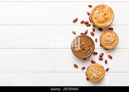 Glasbecher mit Erdnussbutter auf Tischhintergrund, Platz für Text und Nahaufnahmen von oben. Stockfoto