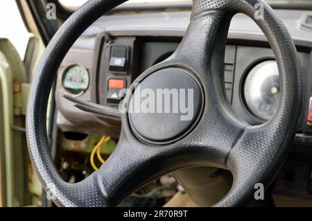 Altes Armaturenbrett des Fahrzeugs der 70er Jahre mit Tachometer, Tasten für Beleuchtung und Ventilator, Lederlenkrad, selektiver Fokus auf altem Jahrgang C. Stockfoto